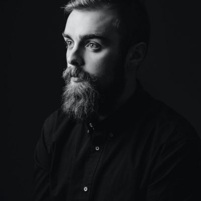 black-and-white-portrait-of-a-stylish-man-with-a-beard-and-stylish-hairdo-dressed-in-the-black-shirt-682x1024